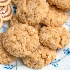 En hög med hembakade havrekakor, perfekta för ett enkelt havrekakor recept. Bredvid syns några rullade kakor med pärlsocker.