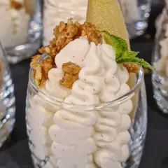 Ljuvlig vispad pannacotta i glas, toppad med krispiga nötter och en bit päron. En perfekt dessert!