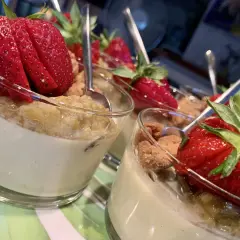 Fluffig pannacotta med rabarber och färska jordgubbar, serverad i glas med en sked.