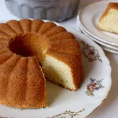 En gyllene sockerkaka, perfekt för ett enkelt sockerkaka recept, ligger på ett vackert fat. En bit är uppskuren.