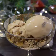 En skål med krämig kokosglass, perfekt för ett hemmagjort kokosglass recept. Julbelysning och gran i bakgrunden.