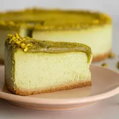 En krämig pistage cheesecake med en krispig botten, toppad med hackade pistagenötter.