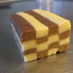 En bit av ett hembakat schackrutemönstrat kex med choklad och vaniljsmak.