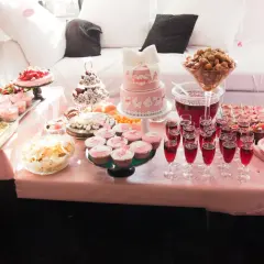 Ett rosa buffébord med många rosa kakor och cupcakes, perfekt för en babyshower.