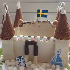 En fantasifull glasstårta formad som ett slott, perfekt för barnkalas. Med svenska flaggan och söta figurer.