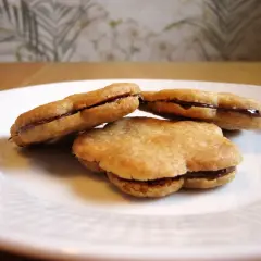 Tre chokladfyllda tuile-kakor på en vit tallrik. Ett enkelt tuile recept som ger läckra småkakor.