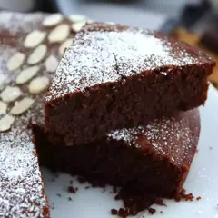 En saftig torta caprese, pudrad med florsocker och garnerad med mandelspån. En dröm för chokladälskare!