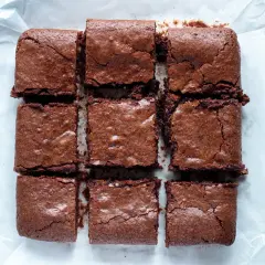 Nio saftiga brownies med choklad, perfekta för ett brownie recept med choklad. Ligger på bakplåtspapper.