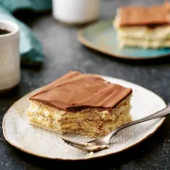 En bit chokladkaka med mariekex och krämig fyllning, perfekt för ett mariekex recept. En kopp kaffe står bredvid.