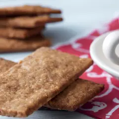 Franska skurna pepparkakor med en kopp kaffe. En stapel av dessa spröda godsaker i bakgrunden.