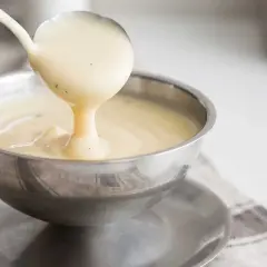 En skopa krämig vaniljsås hälls upp i en skål. Perfekt till efterrätt!