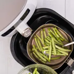 Gröna bönor läggs i en korg för en varm luft ugn.