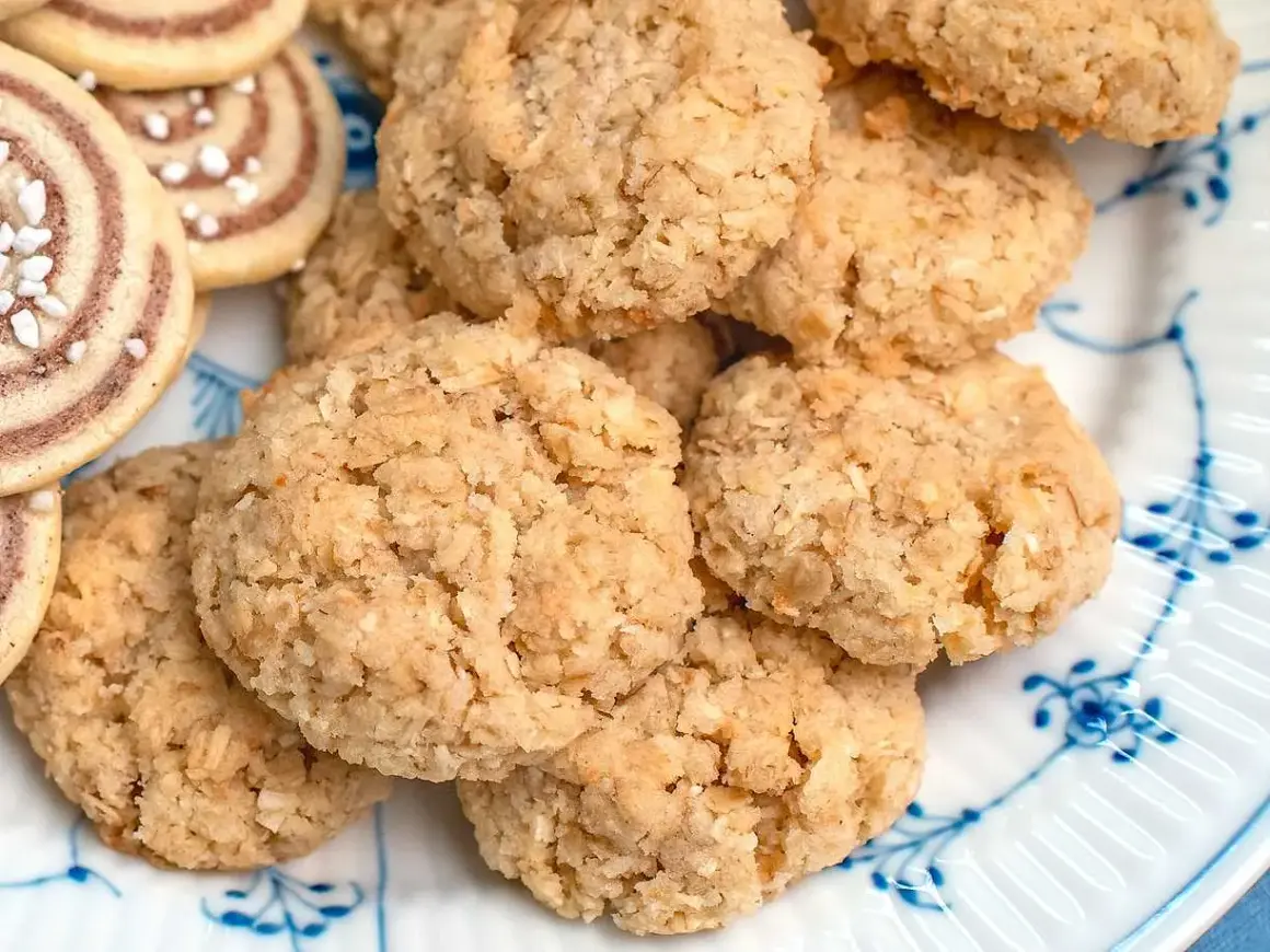En hög med hembakade havrekakor, perfekta för ett enkelt havrekakor recept. Bredvid syns några rullade kakor med pärlsocker.