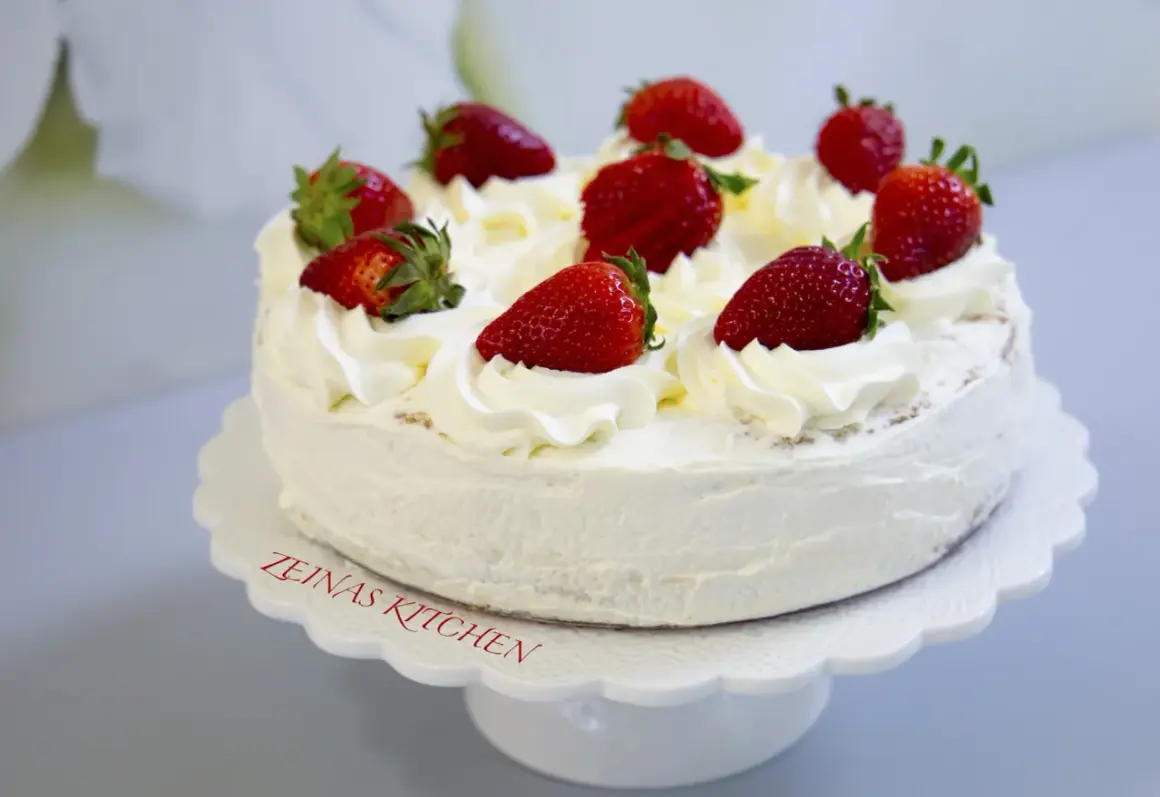 En krämig tres leches-tårta med vispgrädde och färska jordgubbar, perfekt för ett sommarfika.