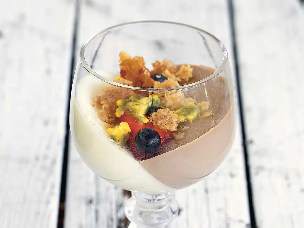 En vacker pannacotta tårta i glas med bär och smulor.
