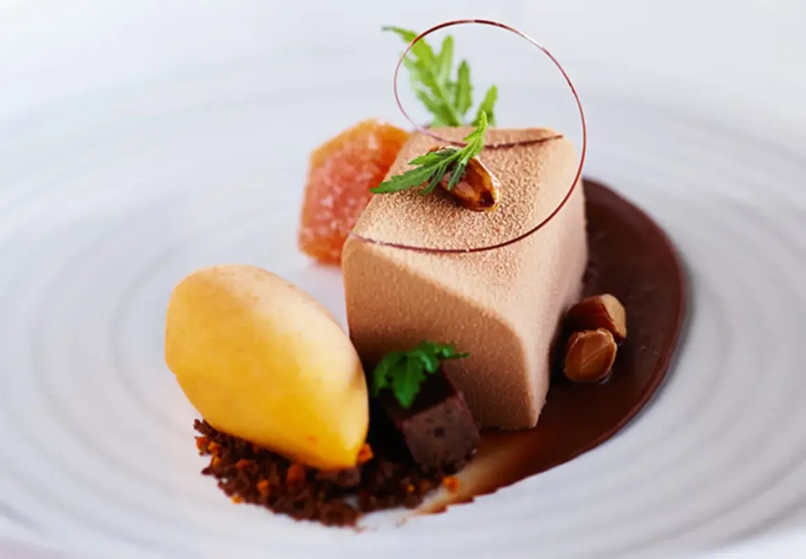 En elegant choklad havtorn dessert med en mousse, sorbet, kanderade nötter och en chokladsås.