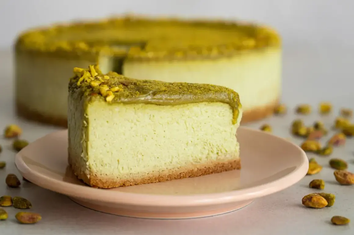 En krämig pistage cheesecake med en krispig botten, toppad med hackade pistagenötter.
