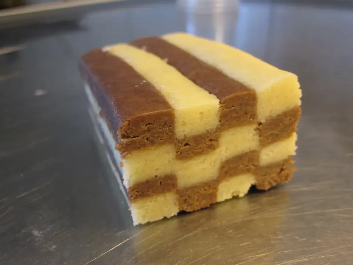 En bit av ett hembakat schackrutemönstrat kex med choklad och vaniljsmak.