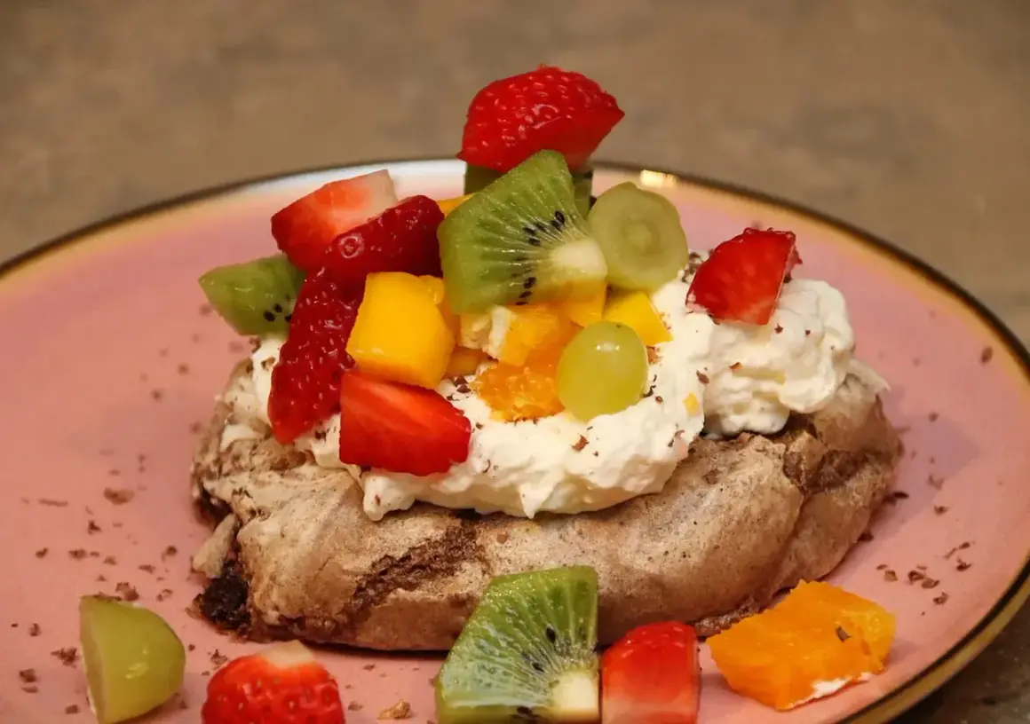 En chokladpavlova med vispgrädde och färsk frukt som jordgubbar, kiwi och mango. En härlig dessert!