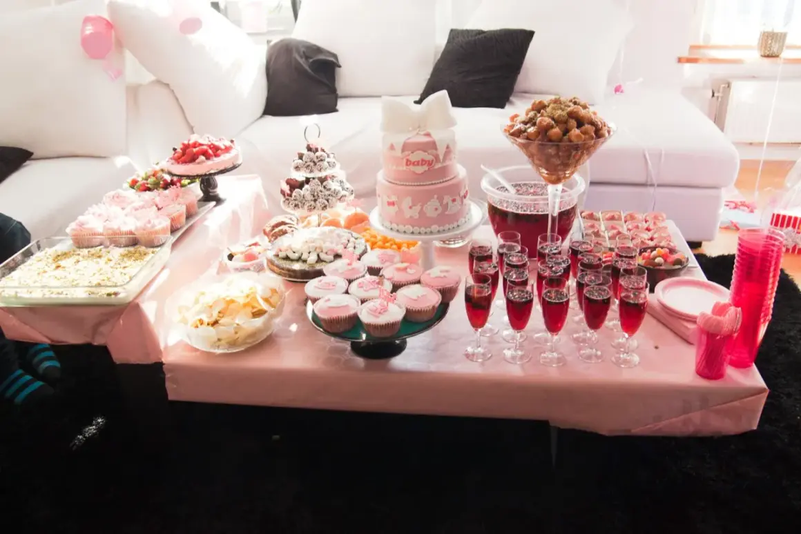 Ett rosa buffébord med många rosa kakor och cupcakes, perfekt för en babyshower.
