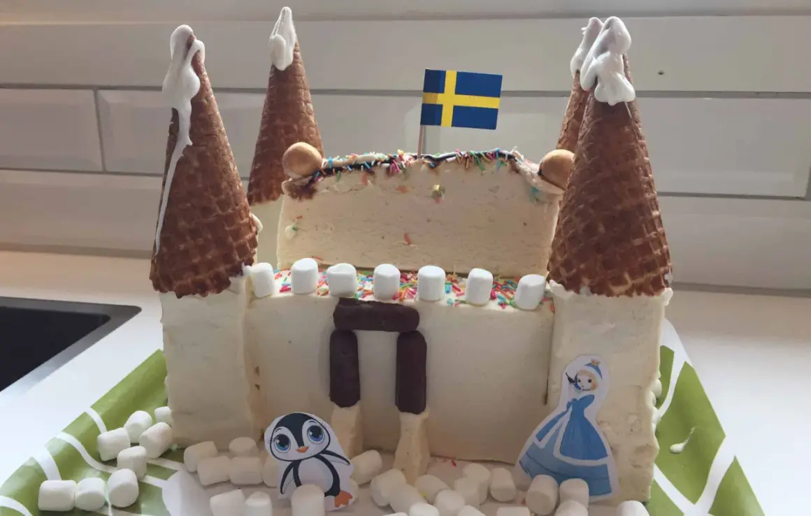 En fantasifull glasstårta formad som ett slott, perfekt för barnkalas. Med svenska flaggan och söta figurer.