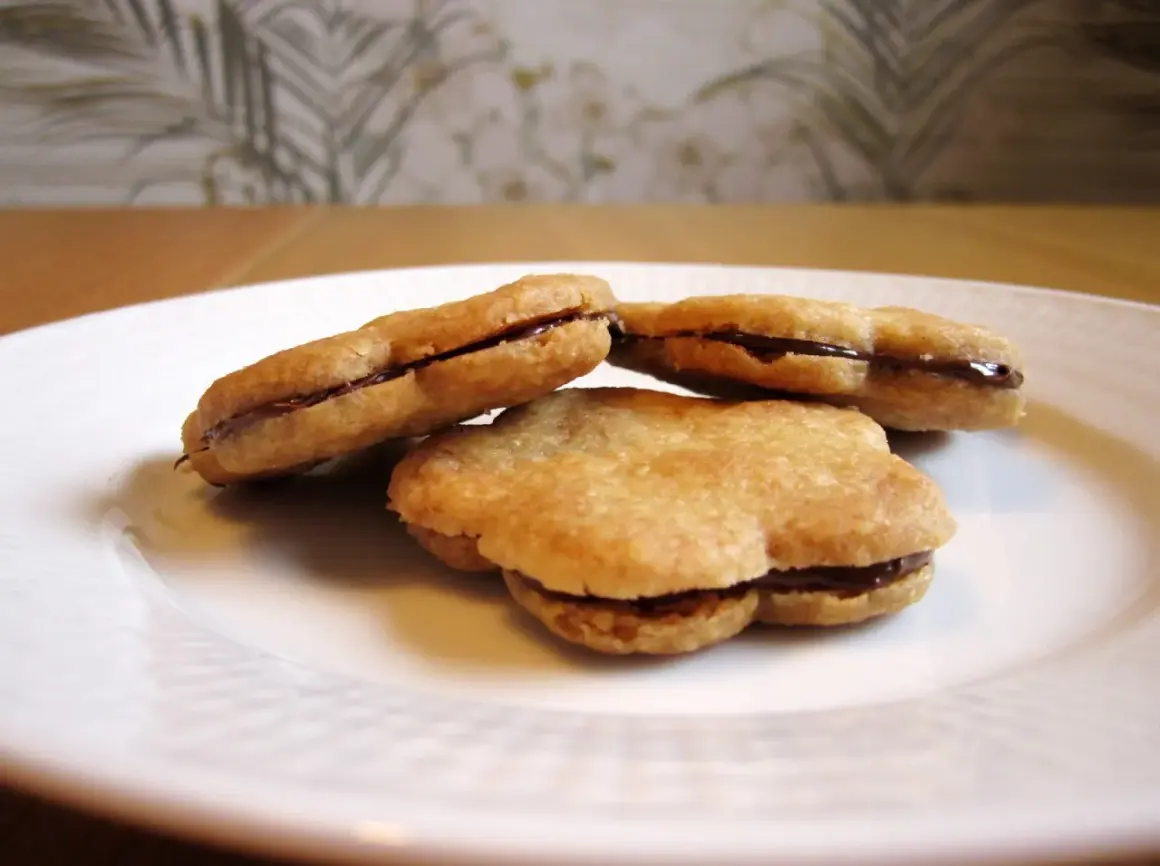 Tre chokladfyllda tuile-kakor på en vit tallrik. Ett enkelt tuile recept som ger läckra småkakor.