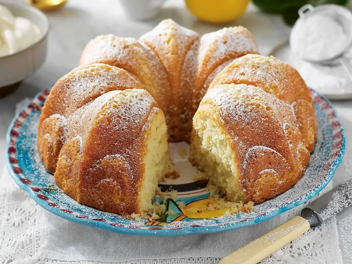 En saftig sockerkaka med yoghurt, pudrad med florsocker, ligger på en vacker blå tallrik.