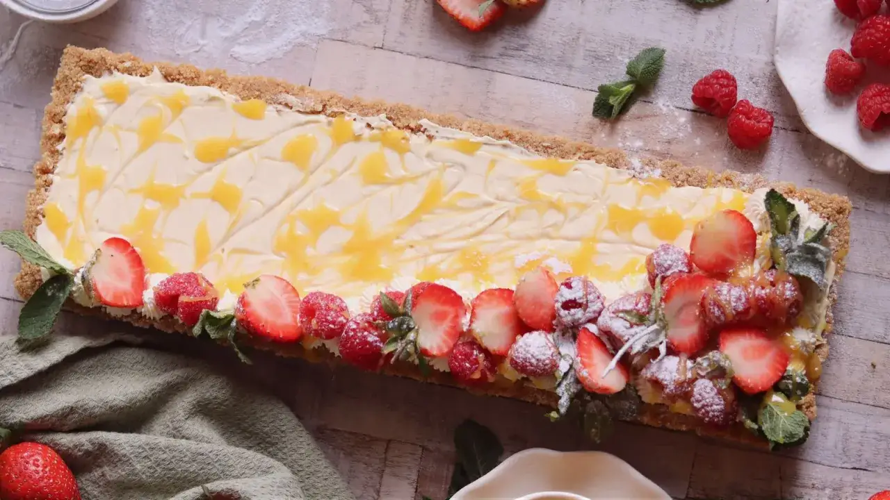 En avl&aring;ng cheesecake med passionsfrukt, toppad med f&auml;rska jordgubbar, hallon och mynta.