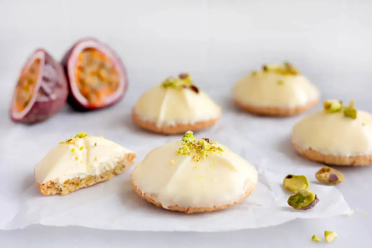 Sm&aring;, vita bakelser med pistaschsmulor och passionsfrukt som inspiration. Perfekt f&ouml;r ett passionsfrukt recept.