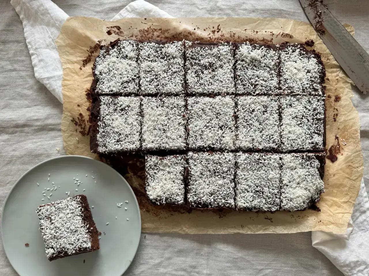 En härlig snoddas kaka, skuren i bitar och toppad med kokosflingor. En bit ligger på en tallrik bredvid.