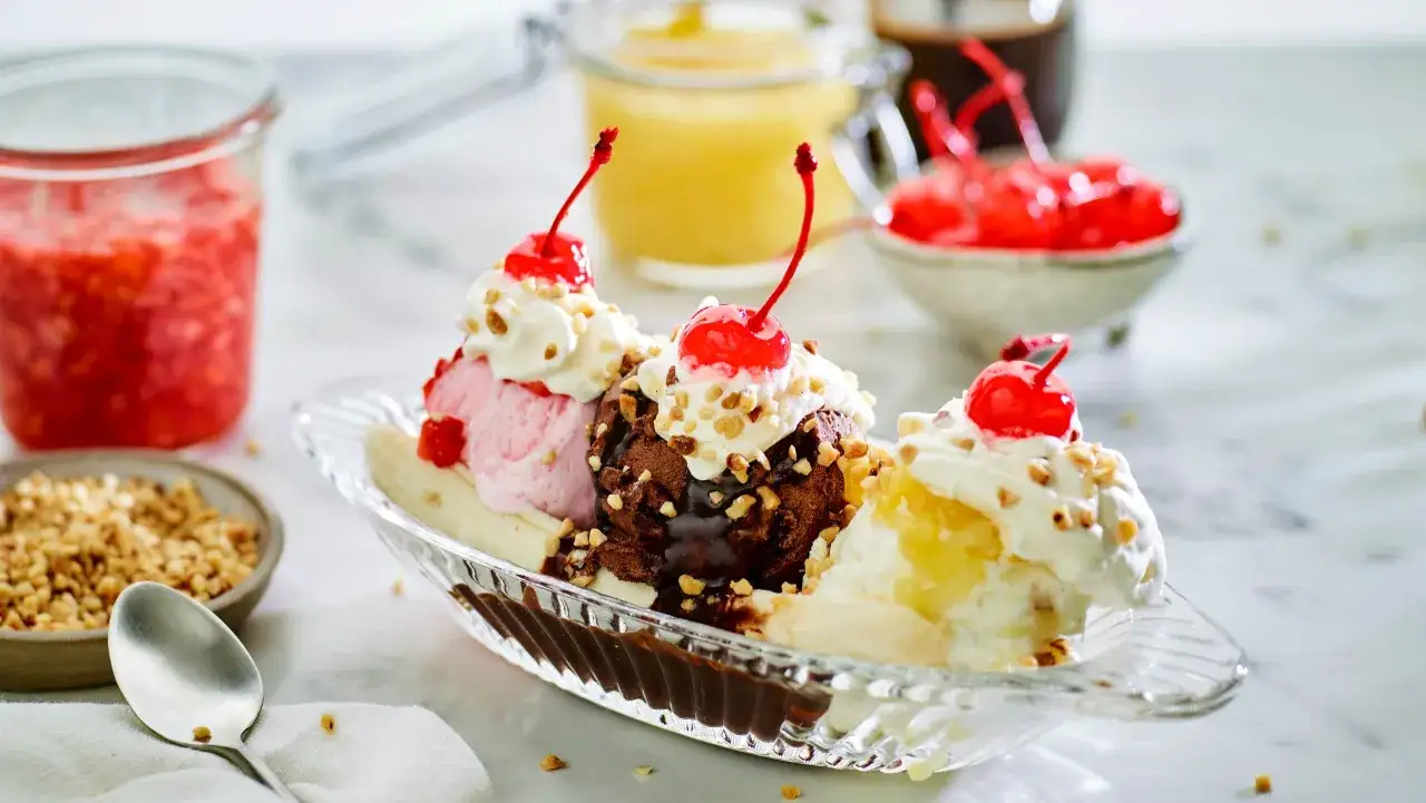 Klassiskt banana split recept med tre kulor glass, banan, grädde, chokladsås, nötter och körsbär.