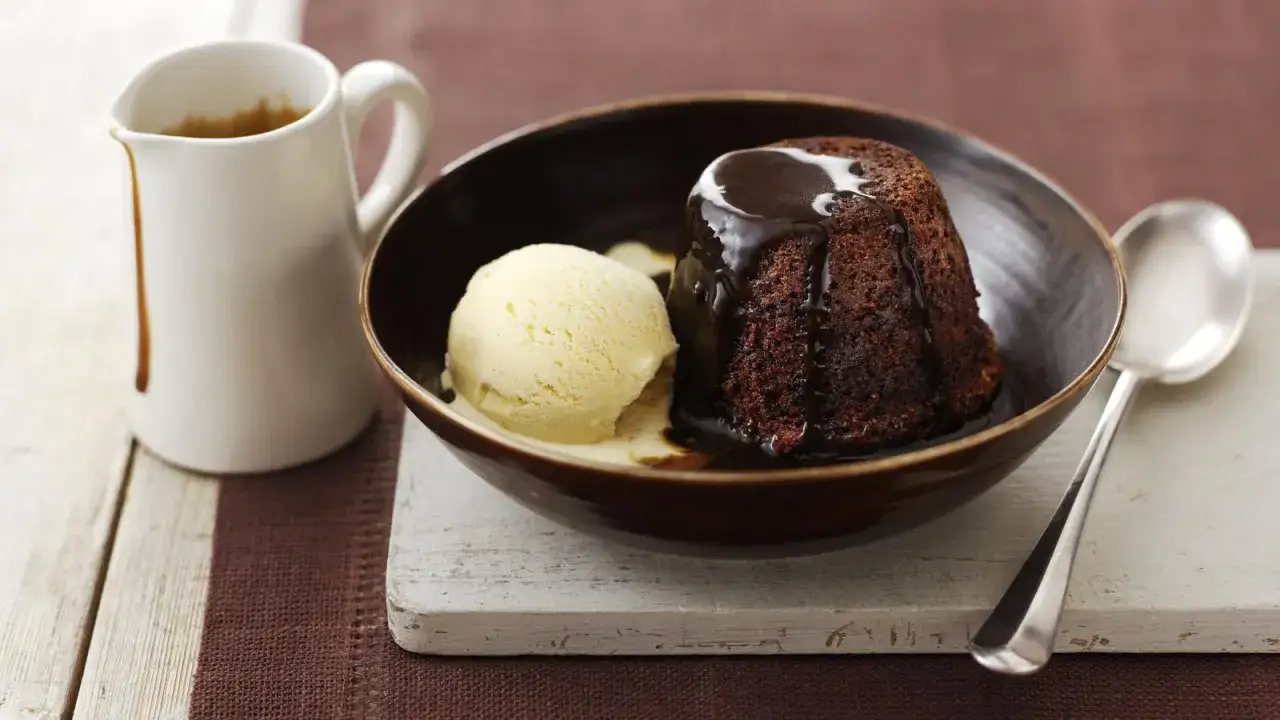 En l&auml;cker chokladpudding med vaniljglass, perfekt f&ouml;r ett sticky toffee pudding recept. En kanna med s&aring;s st&aring;r bredvid.