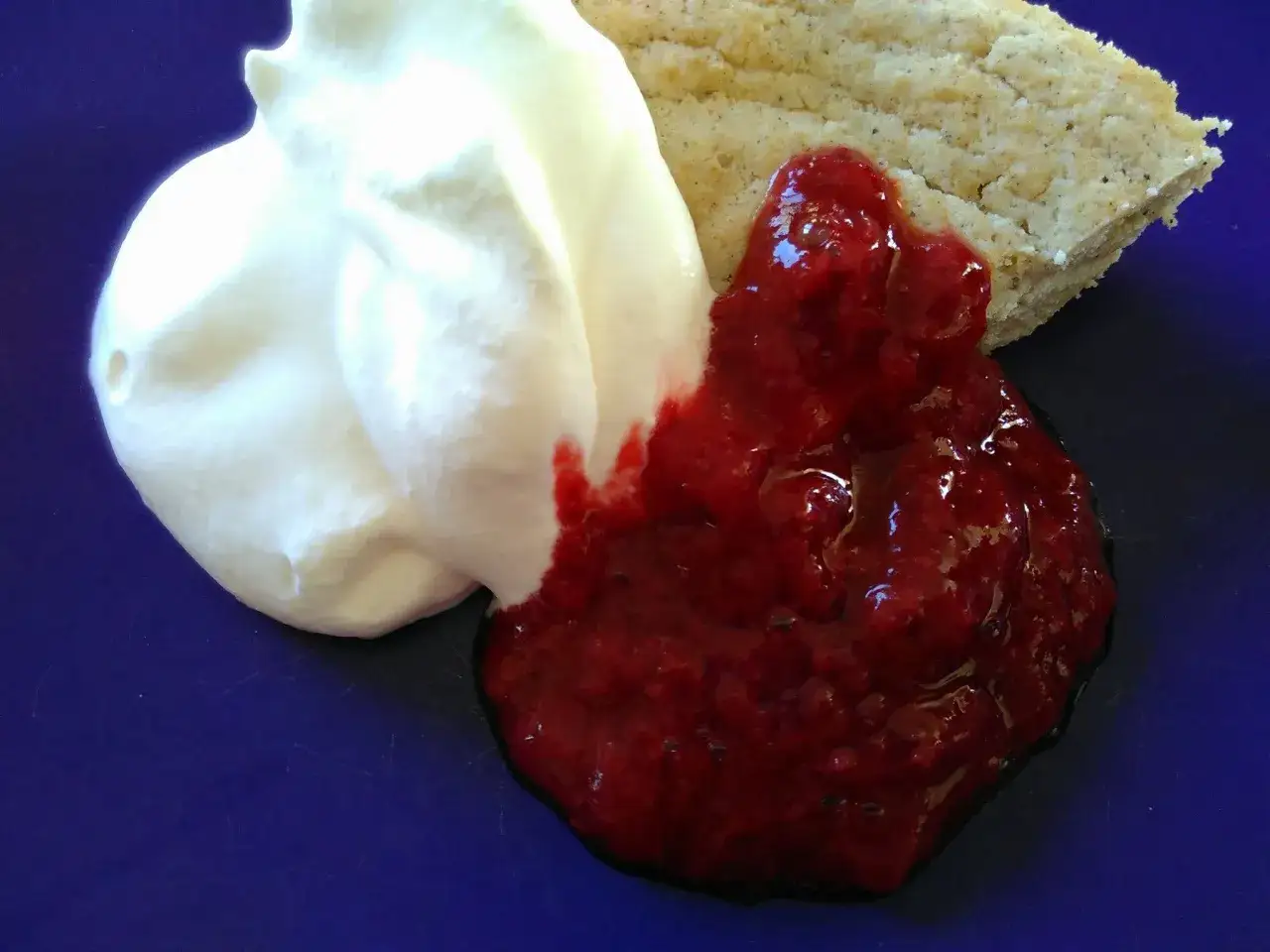 En bit ljus kaka med vispad grädde och hallonsylt, perfekt istället för socker i bakning.