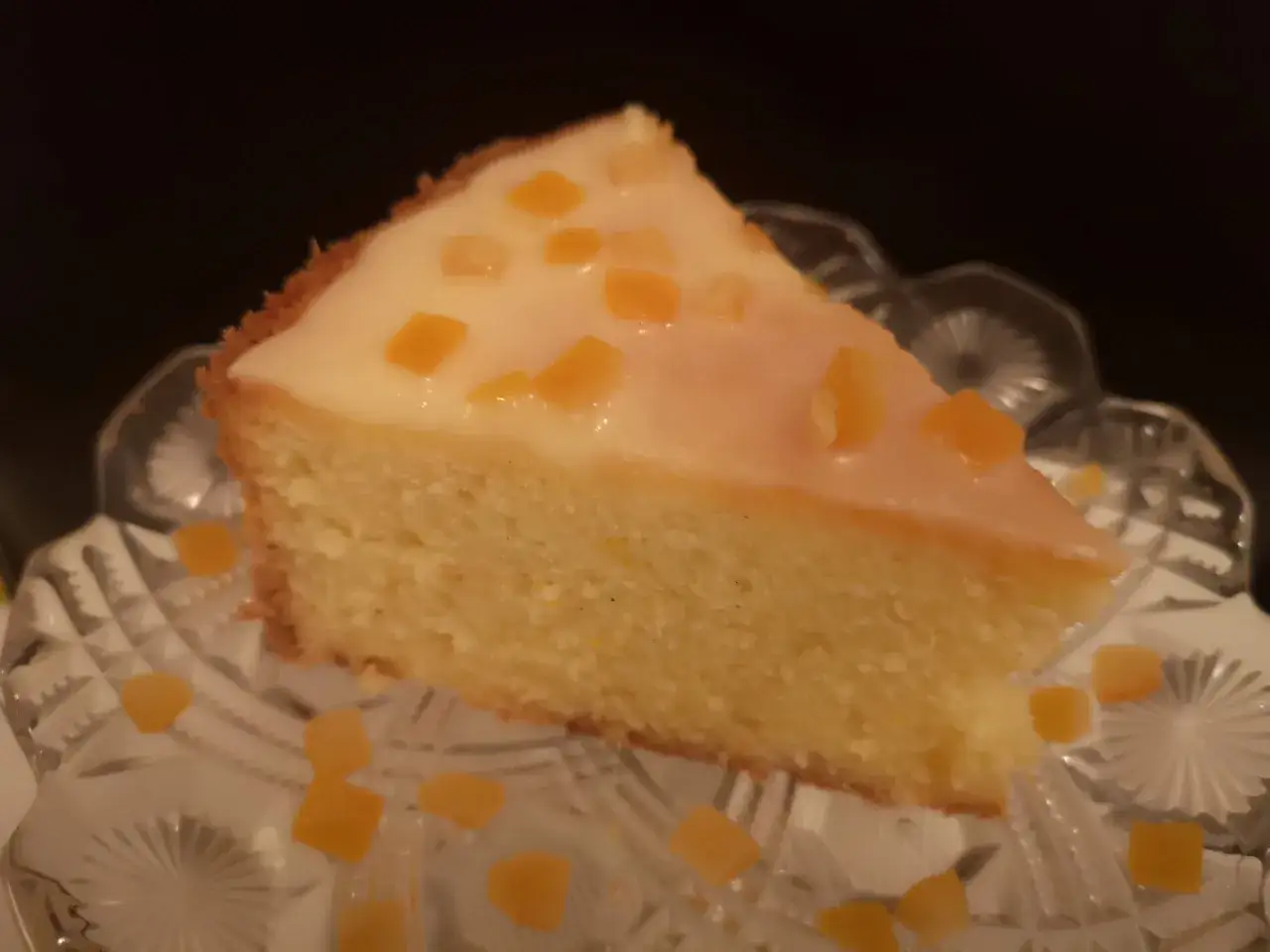 En bit saftig ambrosiakaka i l&aring;ngpanna, toppad med glasyr och kanderad frukt, serverad p&aring; ett vackert fat.