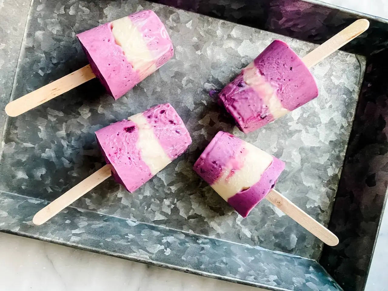 Fyra hemgjorda isglassar med lila och vita lager p&aring; en pl&aring;t. Ett perfekt isglass recept f&ouml;r sommaren!