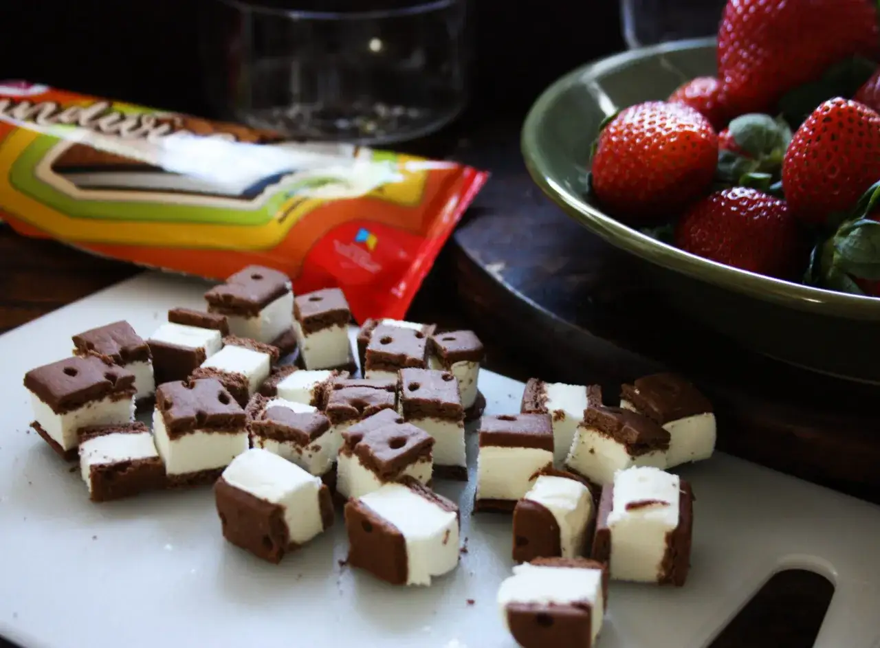 Sm&aring; choklad- och glassbitar, perfekta f&ouml;r en somrig dessert. Jordgubbar i en sk&aring;l i bakgrunden.